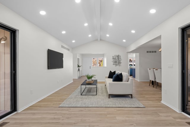 living area featuring visible vents, light wood-type flooring, lofted ceiling with beams, and baseboards