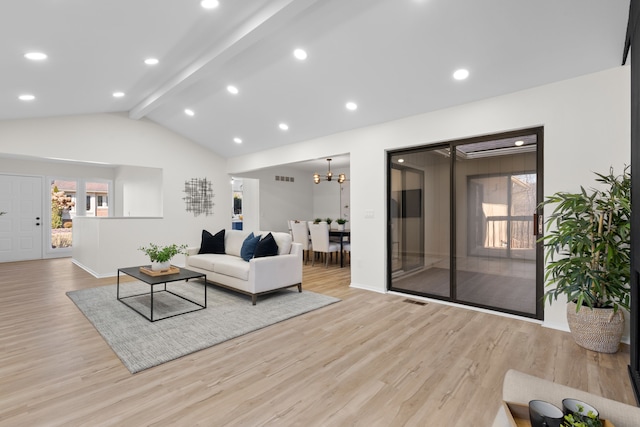 living area featuring lofted ceiling with beams, light wood-type flooring, and plenty of natural light