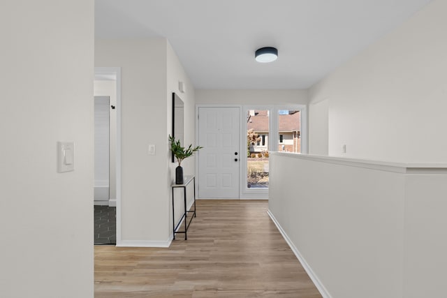 hall featuring light wood-style flooring and baseboards