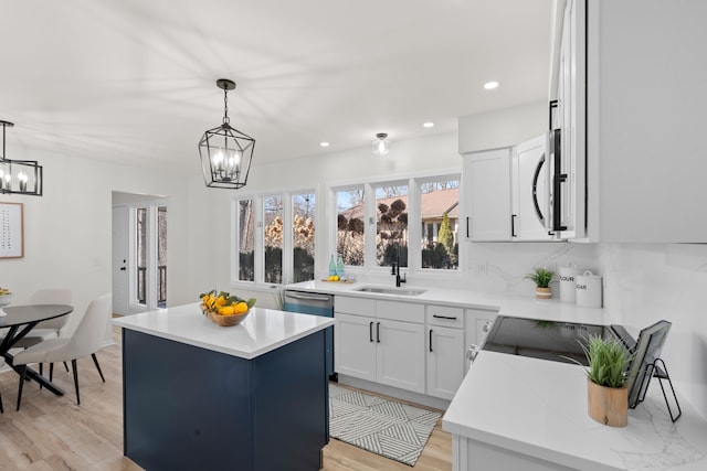 kitchen with a sink, a kitchen island, stainless steel appliances, light countertops, and a chandelier