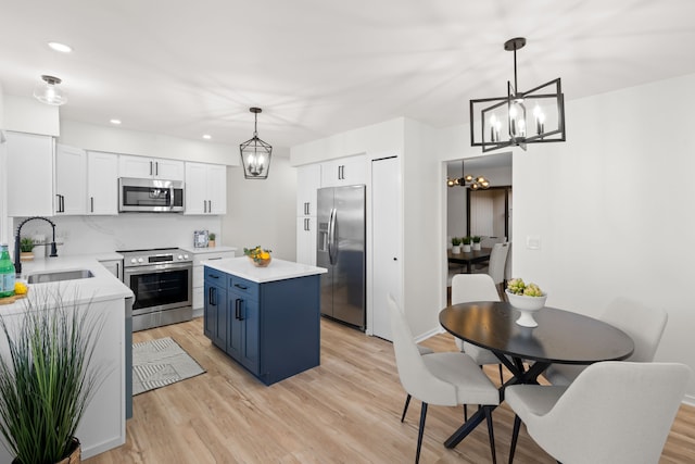 kitchen featuring a sink, stainless steel appliances, a chandelier, and light wood finished floors