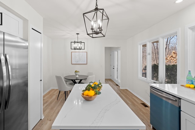 kitchen with white cabinetry, dishwasher, stainless steel refrigerator, and an inviting chandelier