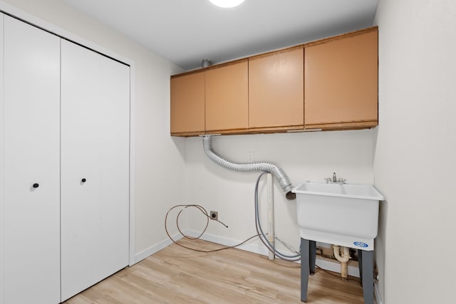 washroom featuring light wood-style flooring, cabinet space, baseboards, and electric dryer hookup