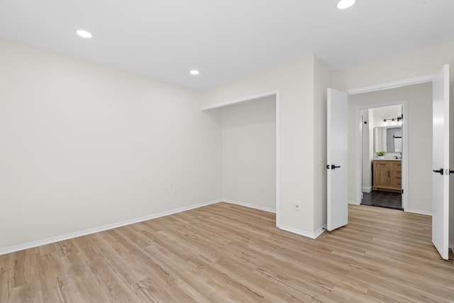 unfurnished bedroom with recessed lighting, light wood-style flooring, and baseboards