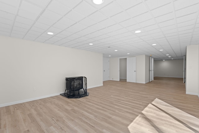 basement with a wood stove, recessed lighting, baseboards, and light wood-type flooring