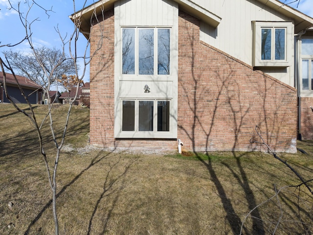 back of property featuring a lawn and brick siding