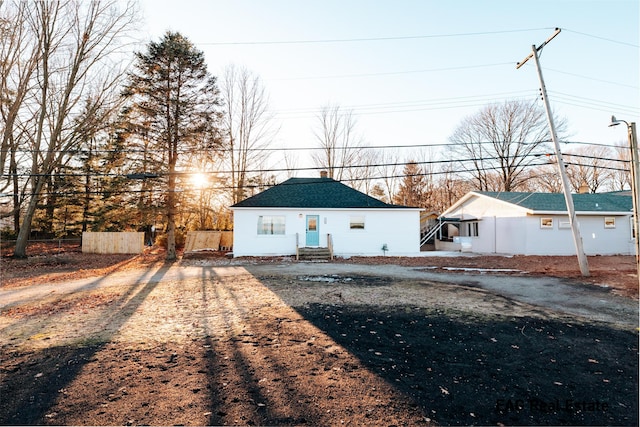 view of front of home with dirt driveway and fence