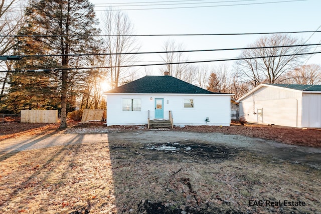 view of front of home featuring a shingled roof, fence, a chimney, and dirt driveway