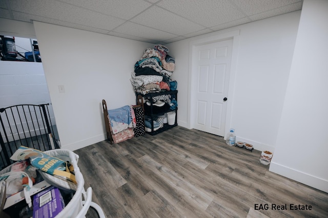 interior space featuring a drop ceiling, wood finished floors, and baseboards