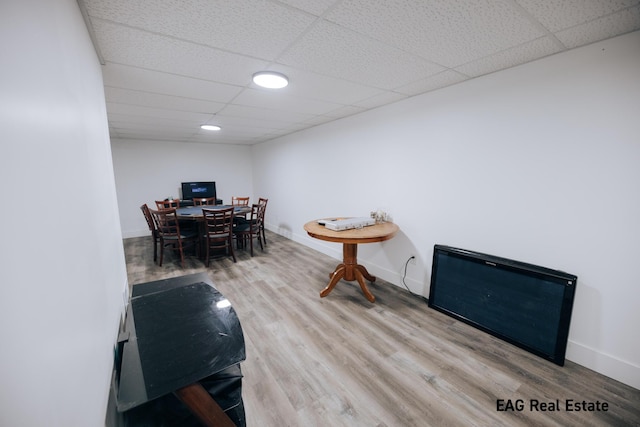 dining area featuring a drop ceiling, wood finished floors, and baseboards