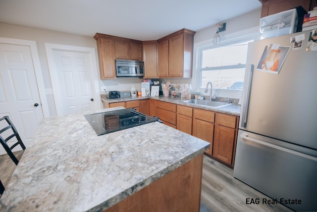 kitchen with stainless steel appliances, light wood-style flooring, a sink, and light countertops