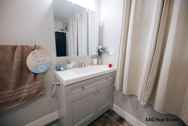 bathroom with baseboards, wood finished floors, and vanity