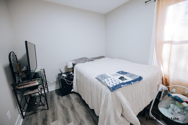 bedroom featuring multiple windows, baseboards, and wood finished floors