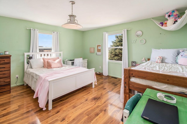 bedroom with baseboards, multiple windows, visible vents, and light wood-style floors