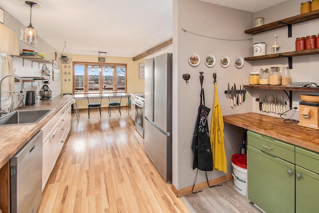 kitchen featuring open shelves, appliances with stainless steel finishes, a sink, and wooden counters