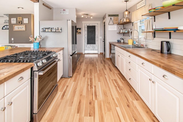 kitchen with white cabinets, butcher block counters, open shelves, a sink, and gas stove