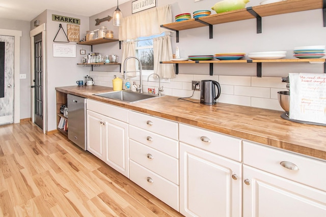 kitchen featuring open shelves, butcher block counters, a sink, and stainless steel dishwasher