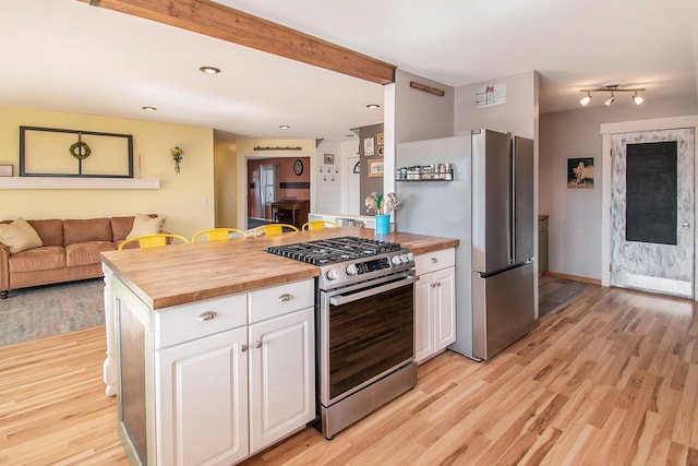 kitchen with butcher block counters, appliances with stainless steel finishes, white cabinets, and light wood-style flooring