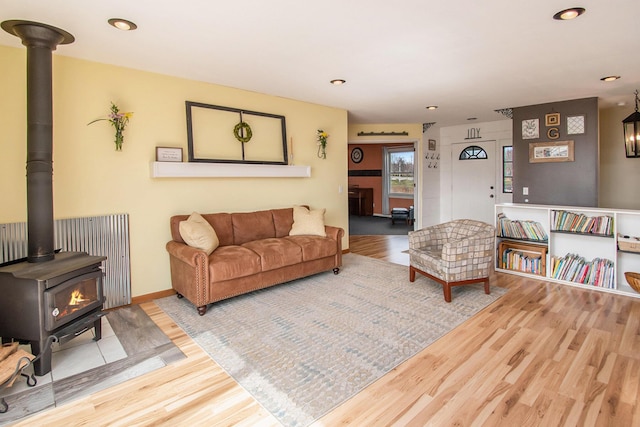 living area with recessed lighting, wood finished floors, a wood stove, and baseboards