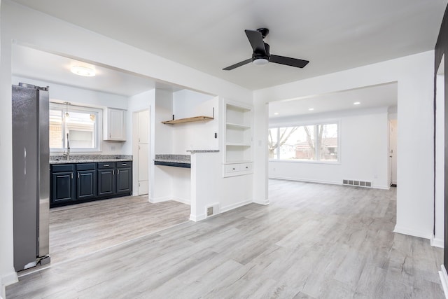 kitchen with light wood-style floors, visible vents, freestanding refrigerator, and open floor plan