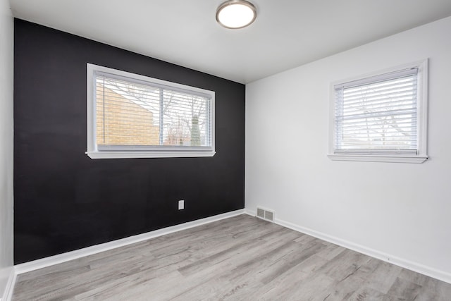 empty room featuring baseboards, visible vents, and light wood-type flooring