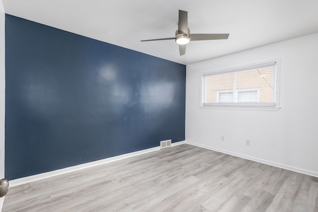 spare room featuring a ceiling fan, wood finished floors, visible vents, and baseboards