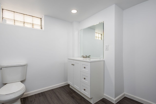 half bath with baseboards, toilet, wood finished floors, and plenty of natural light