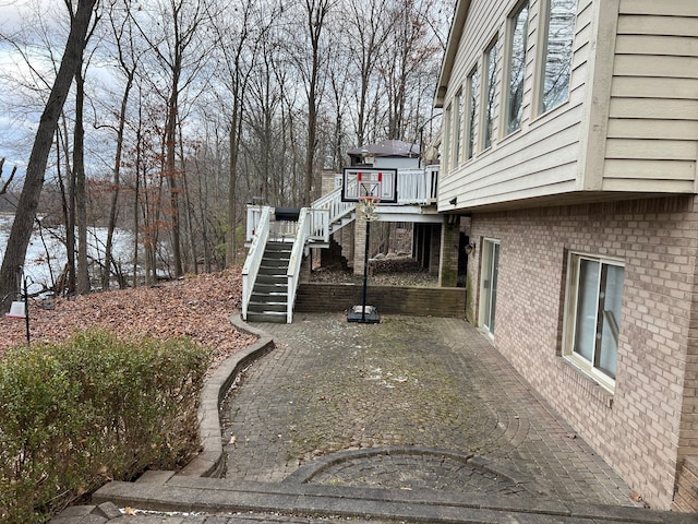 view of side of property featuring brick siding, stairs, and a wooden deck