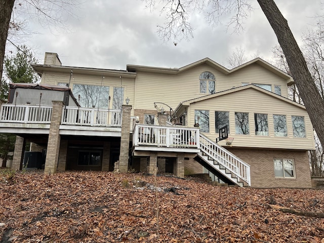 rear view of property with stairway, a deck, and brick siding