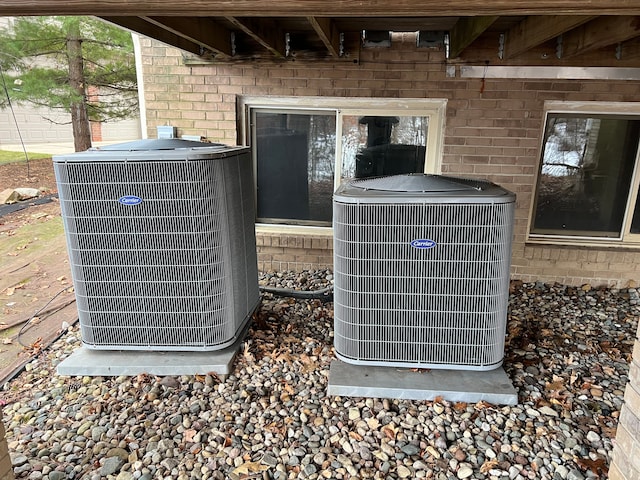 exterior details featuring central AC and brick siding