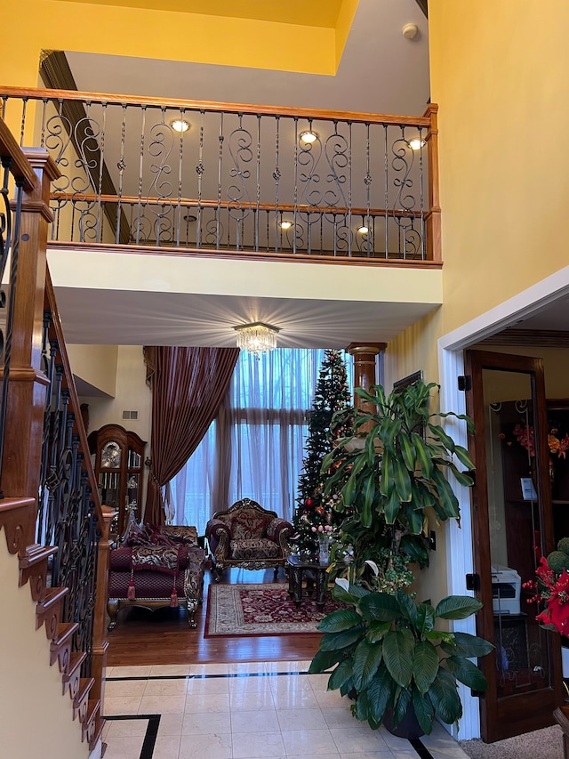 interior space with tile patterned flooring, visible vents, a towering ceiling, and stairs