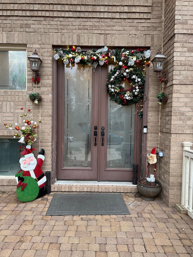 doorway to property with french doors, roof with shingles, and brick siding