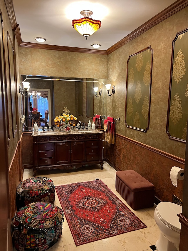 bathroom with toilet, ornamental molding, wainscoting, and vanity