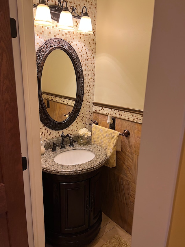 half bathroom with tile patterned flooring, wainscoting, tile walls, and vanity