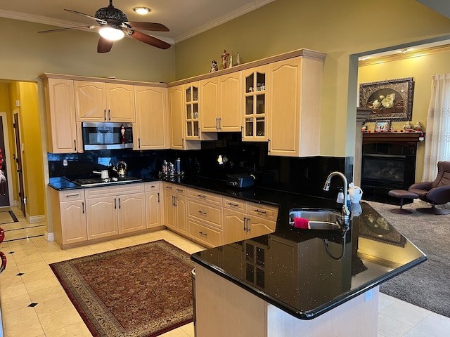 kitchen with stainless steel microwave, ornamental molding, a glass covered fireplace, a sink, and a peninsula