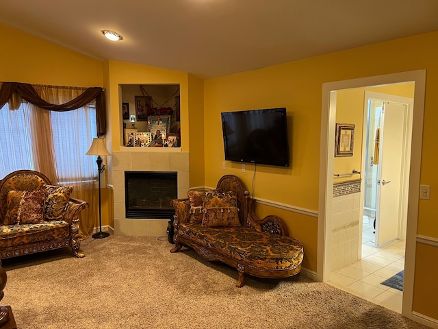 sitting room with lofted ceiling, a tiled fireplace, carpet flooring, and tile patterned flooring