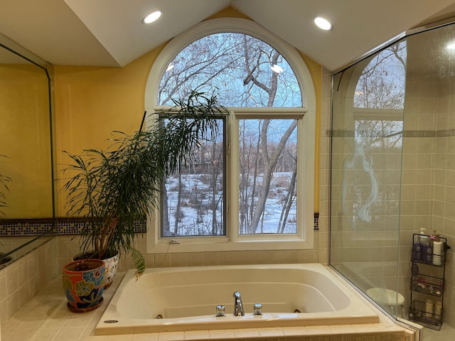 bathroom with vaulted ceiling, a jetted tub, and a wealth of natural light