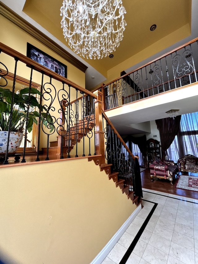 staircase featuring baseboards, a tray ceiling, and a notable chandelier