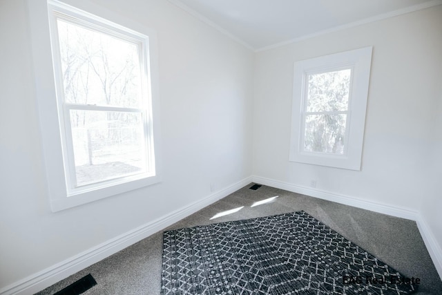 interior space featuring baseboards, ornamental molding, and dark colored carpet