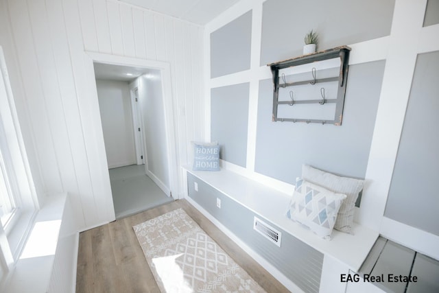 mudroom with wooden walls and wood finished floors