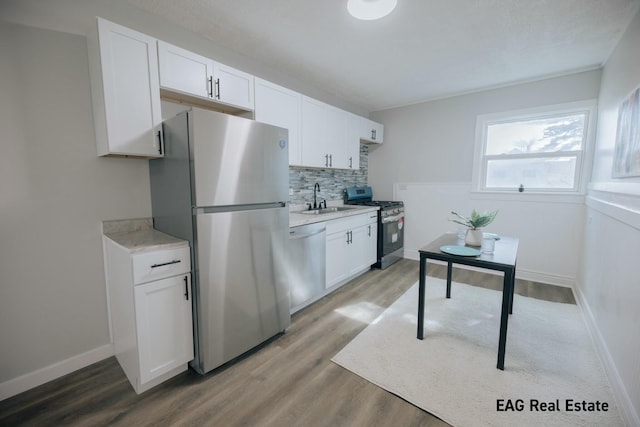 kitchen featuring appliances with stainless steel finishes, light countertops, a sink, and tasteful backsplash