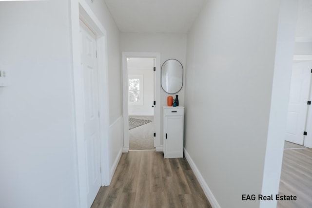 corridor featuring wood finished floors and baseboards