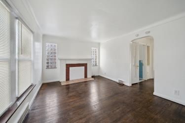 unfurnished living room with a fireplace with flush hearth, wood finished floors, baseboards, and arched walkways