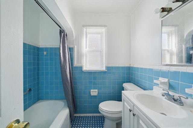 bathroom with vanity, a wainscoted wall, tile walls, toilet, and shower / tub combo with curtain