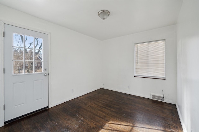 unfurnished room featuring visible vents, baseboards, and dark wood-style flooring