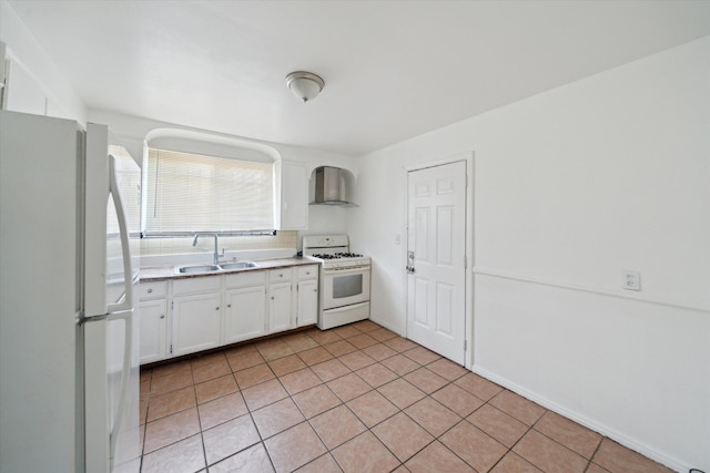 kitchen with wall chimney range hood, light tile patterned flooring, white cabinets, white appliances, and a sink