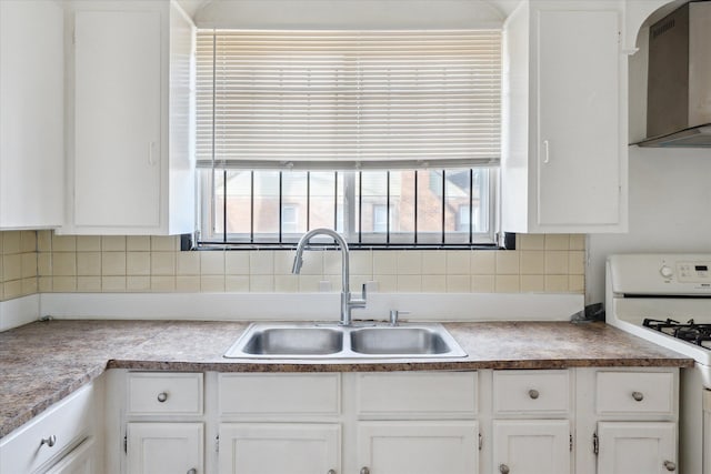 kitchen featuring white cabinetry, range hood, white gas stove, and a sink