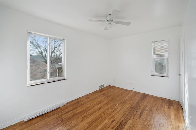 empty room with light wood finished floors, visible vents, baseboards, and ceiling fan