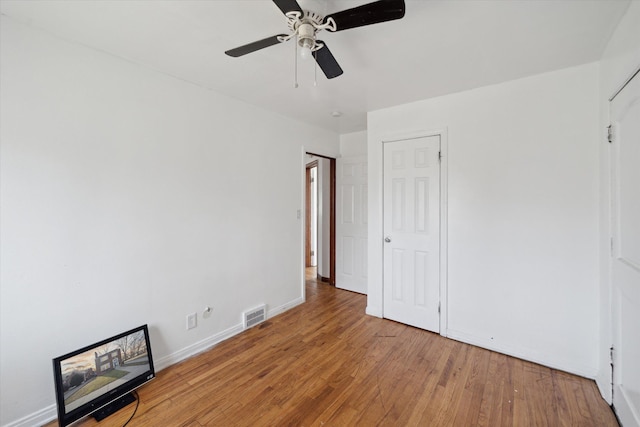 unfurnished bedroom featuring ceiling fan, visible vents, baseboards, and wood finished floors