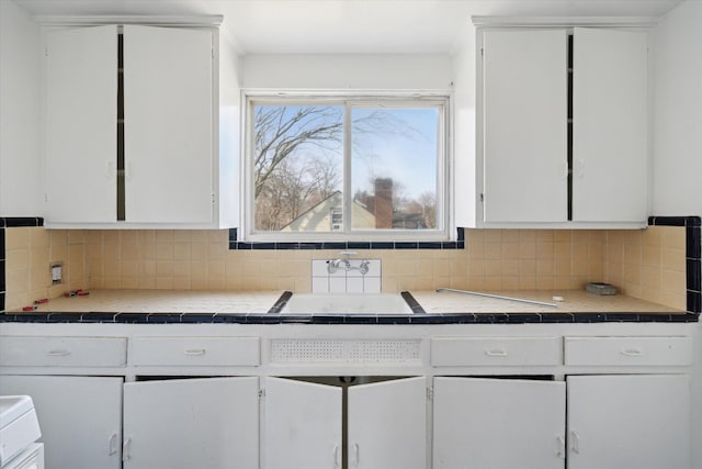 kitchen featuring tasteful backsplash, white cabinets, and tile counters